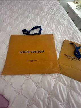 Set of Louis Vuitton paper bags with blue handles.